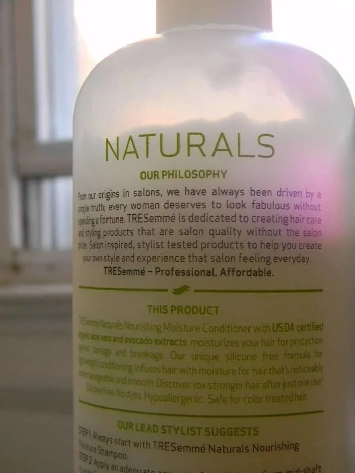 Bottle of TRESemmé Naturals conditioner with text describing its philosophy of providing professional, affordable hair care products