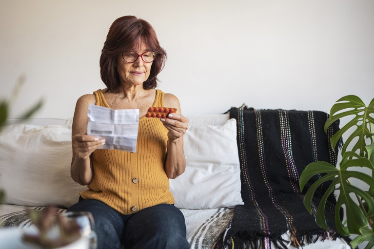 A woman in a home setting reviews materials for hormone replacement therapy.