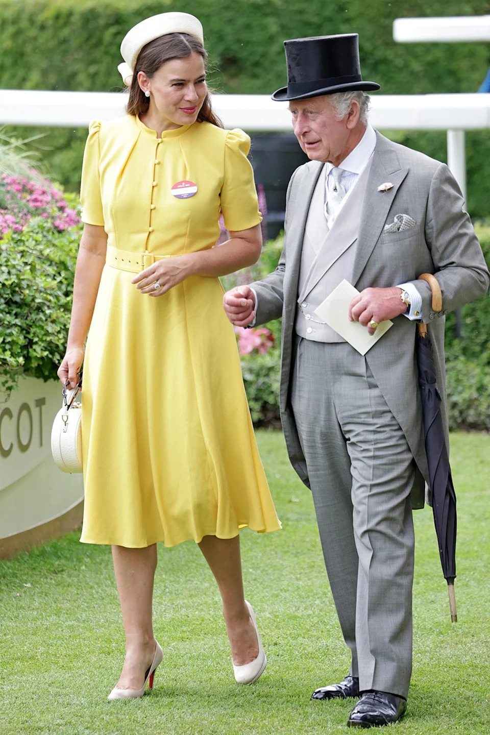 Sophie Winkleman in a yellow dress walking alongside King Charles.