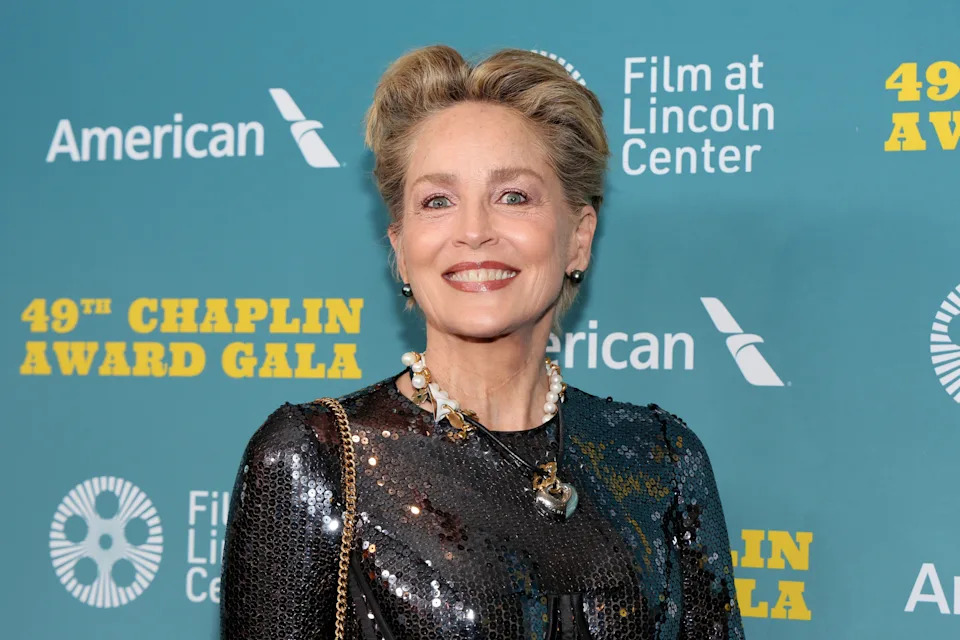 A person at the Chaplin Award Gala wearing a shimmering sequined dress and pearl necklace, posing for photos on the event's media wall