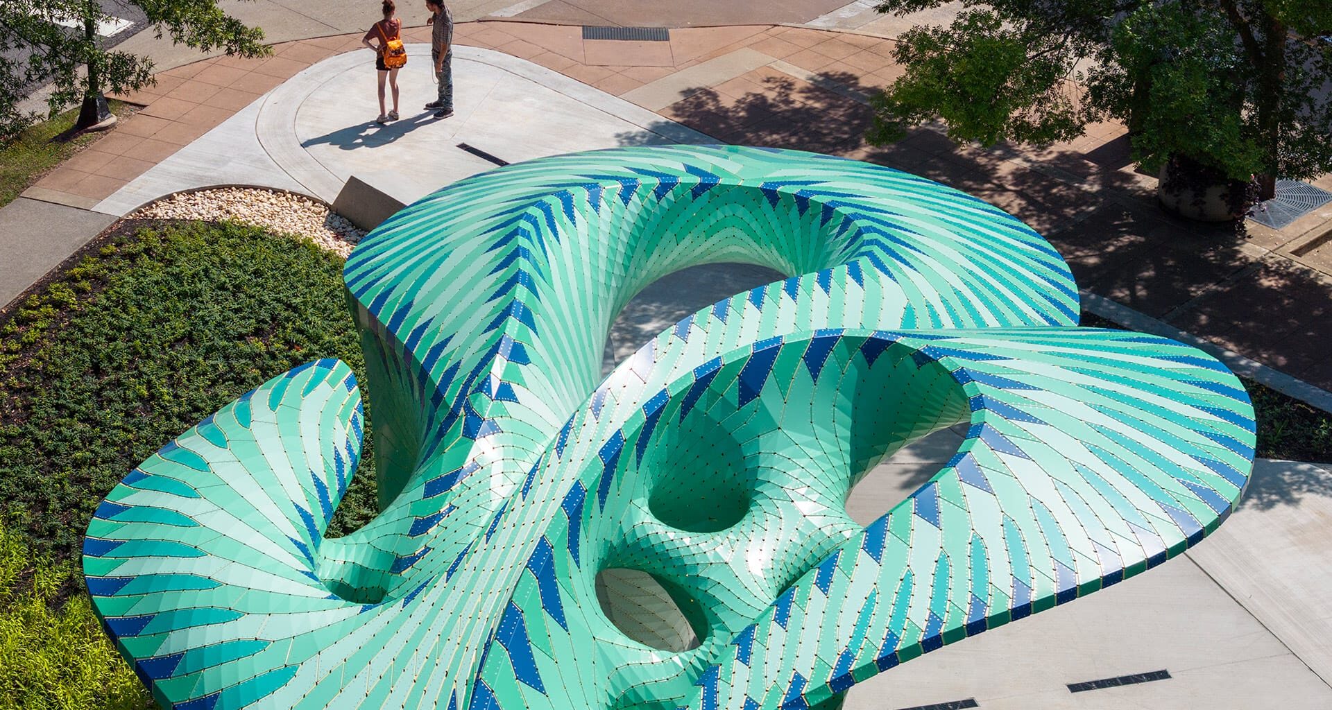 an aerial view of a contemporary, teal-colored pavilion designed by Marc Fornes/THEVERYMANY in a public square in Knoxville, Tennessee
