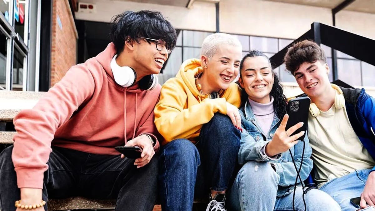 Four Gen Z adults sit on steps while talking and laughing together