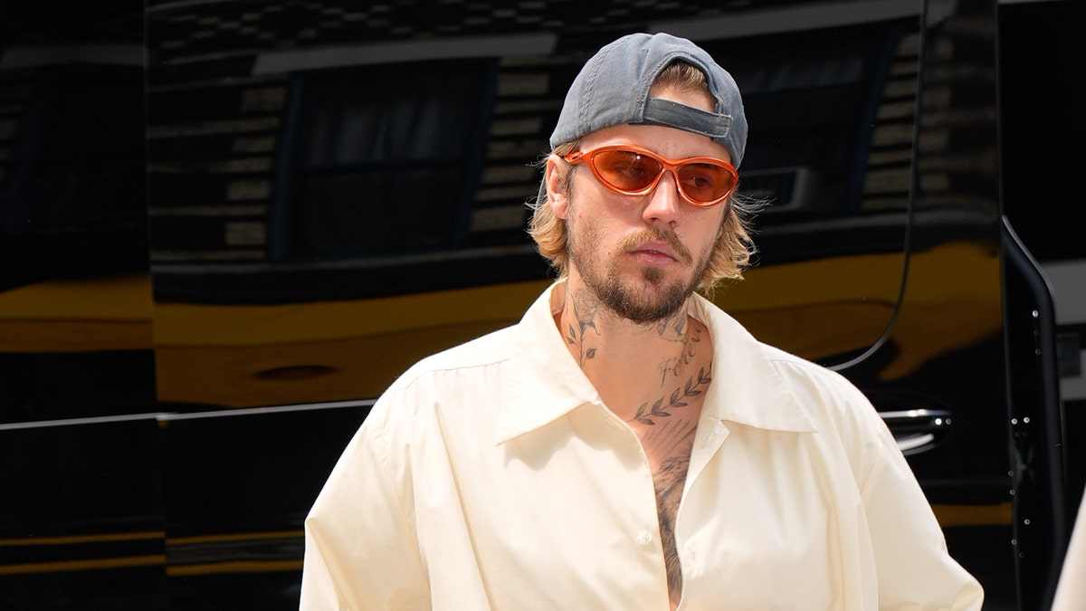 Justin Bieber wears a white shirt, sunglasses and a hat