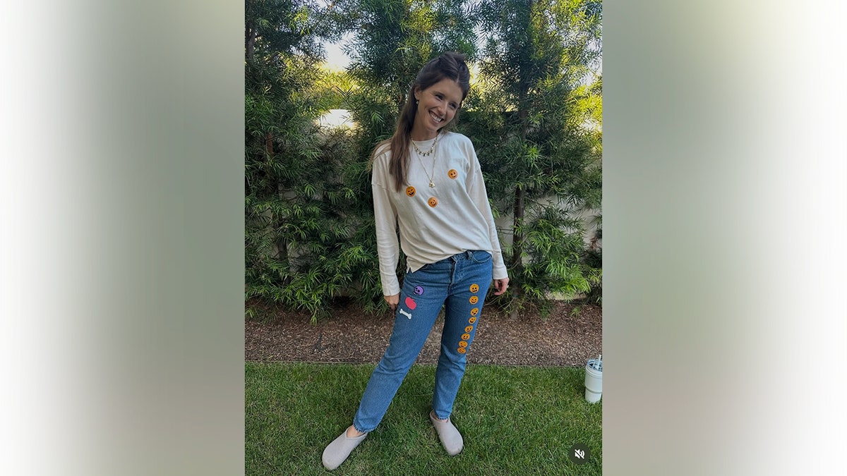 Katherine Schwarzenegger smiling in a blouse and jeans with Halloween stickers