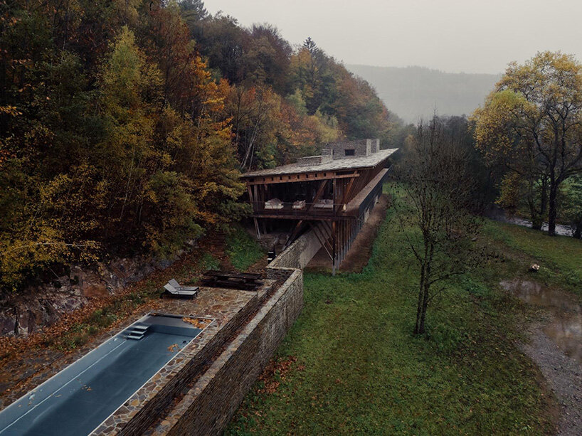 local stone and timber shape self-sufficient riverbank house by BC architects in belgium