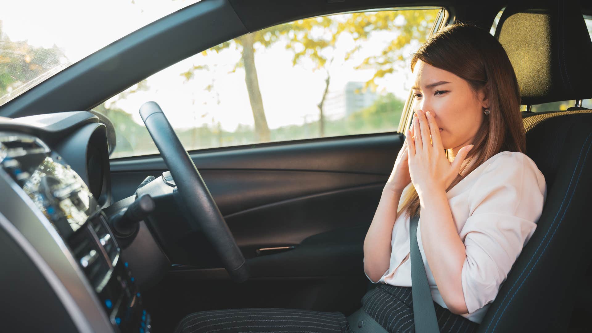 woman in friend's car smelling something gross