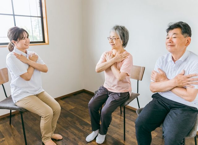 Seniors and elderly men and women doing chair exercises, exercises and rehabilitation to maintain muscle strength and physical fitness at a nursing facility, along with physical therapists