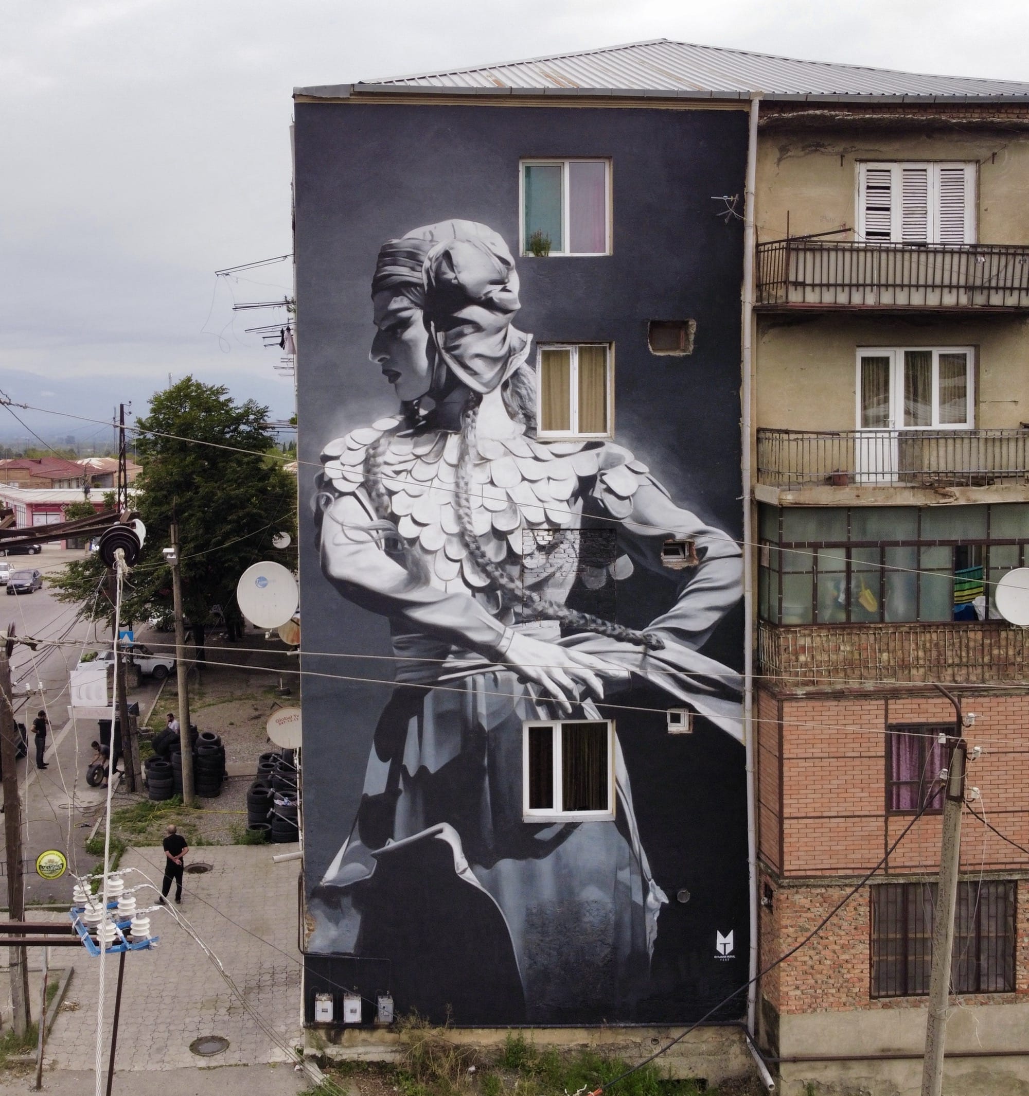 a black-and-white mural on the side of a building of a woman dancing
