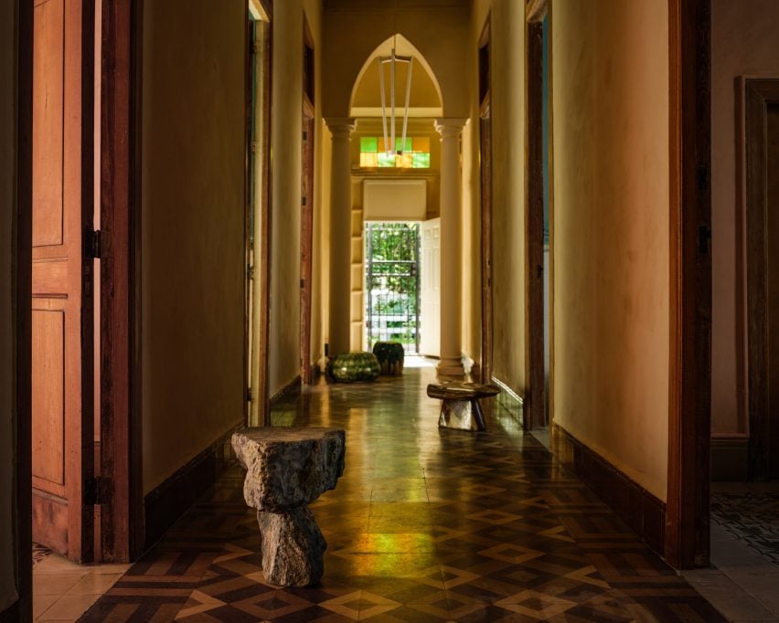 Corridor of a historic villa with small tables and stools on the decorative tiles