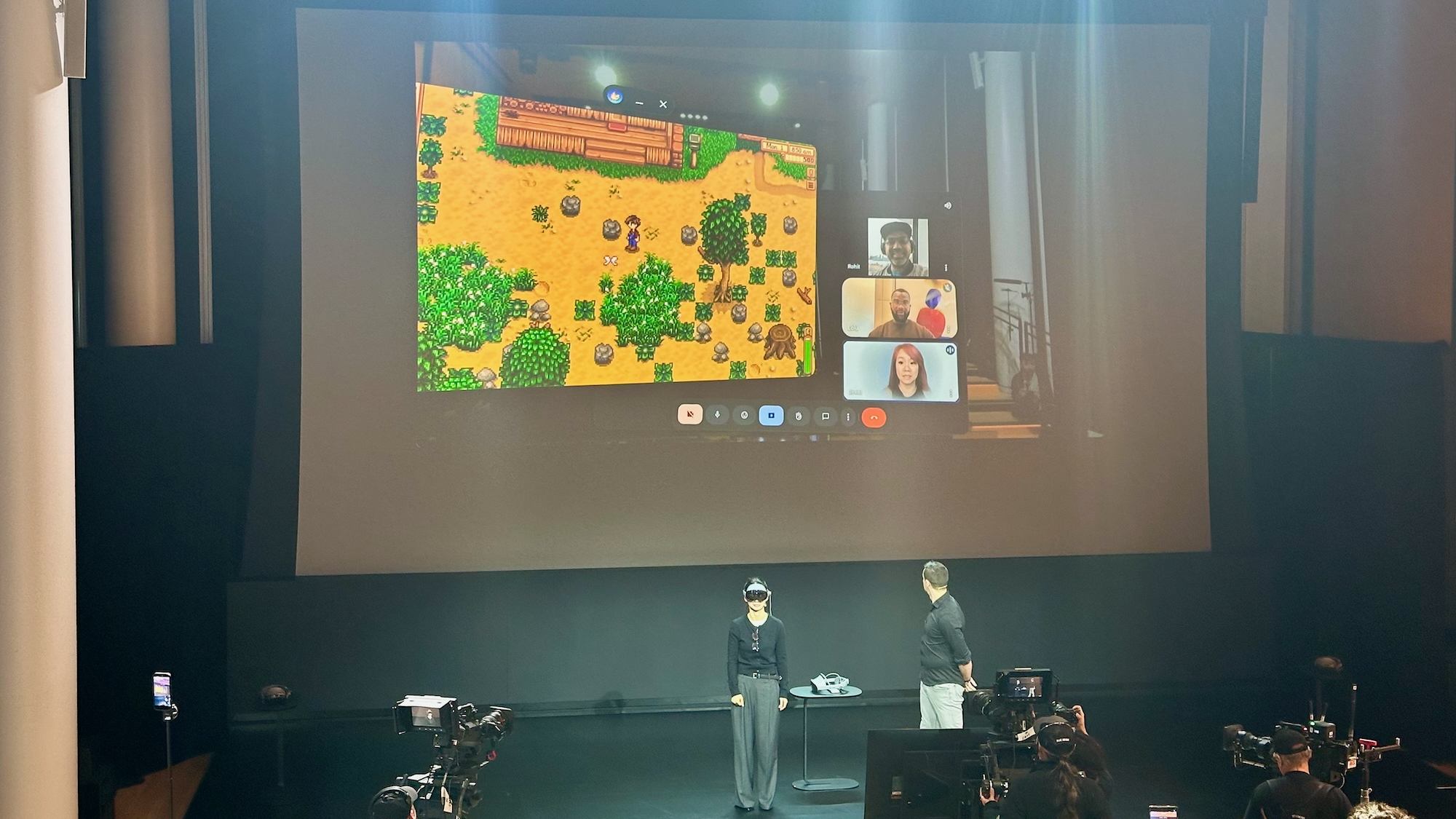 A photo of a Samsung engineer playing Stardew Valley on stage at a Samsung Galaxy XR event, wearing the headset while speaking to friends on a Google Meet call.