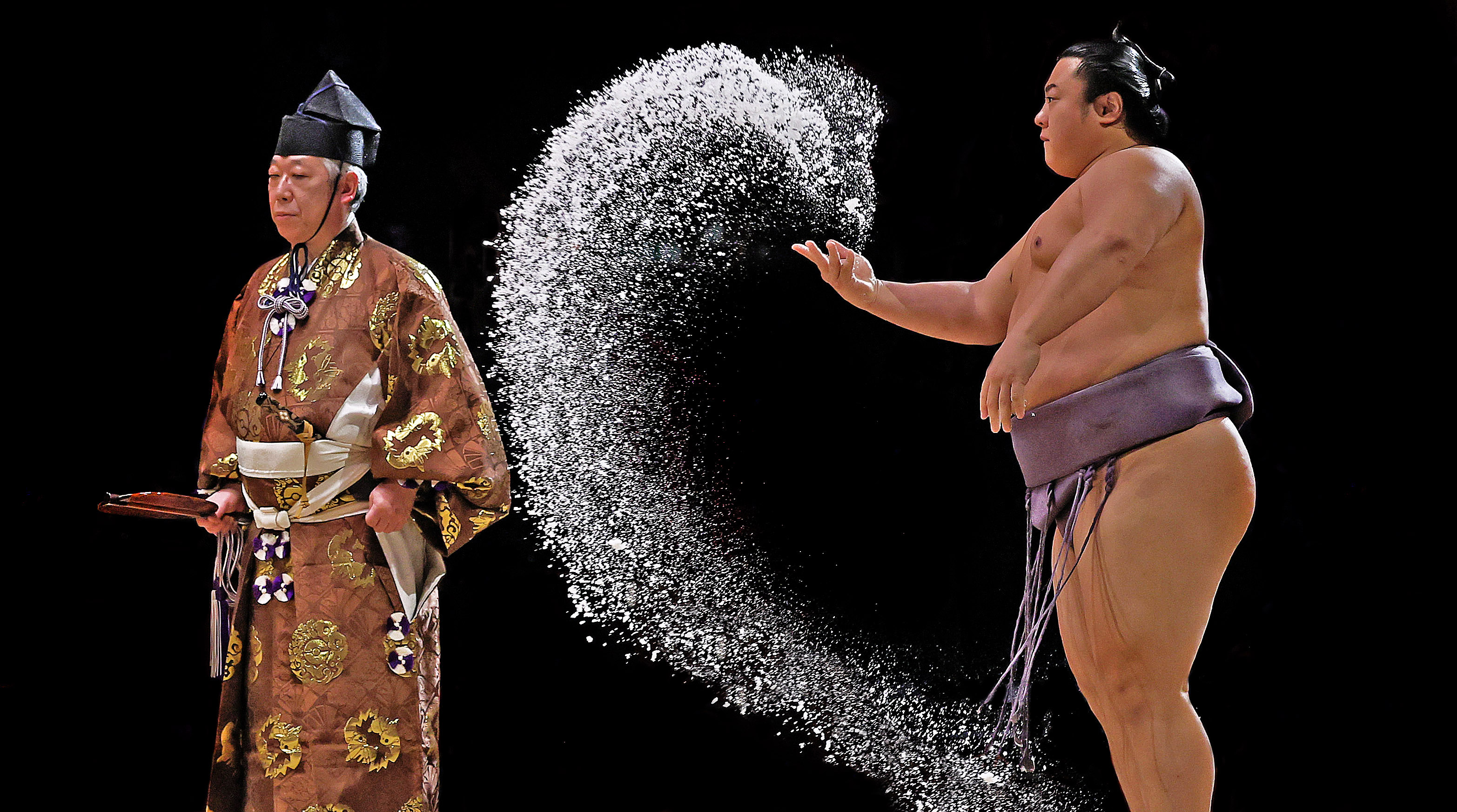 Sumo wrestler Hoshoryu throwing salt while a referee in traditional attire watches.
