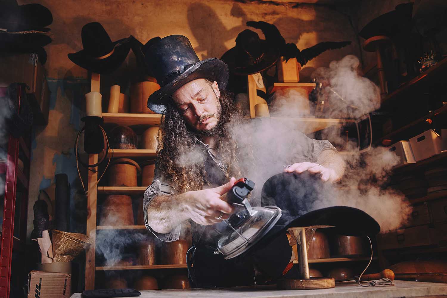 Hatter Paul Ventress shaping felt hats using steam in his York studio.