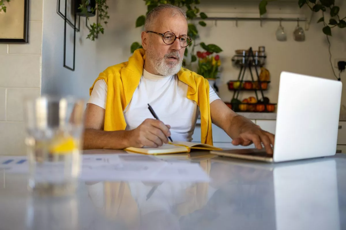 Senior man using laptop at home. Digitally managing of pension concept. Financial problems, monthly pension, paying bills.