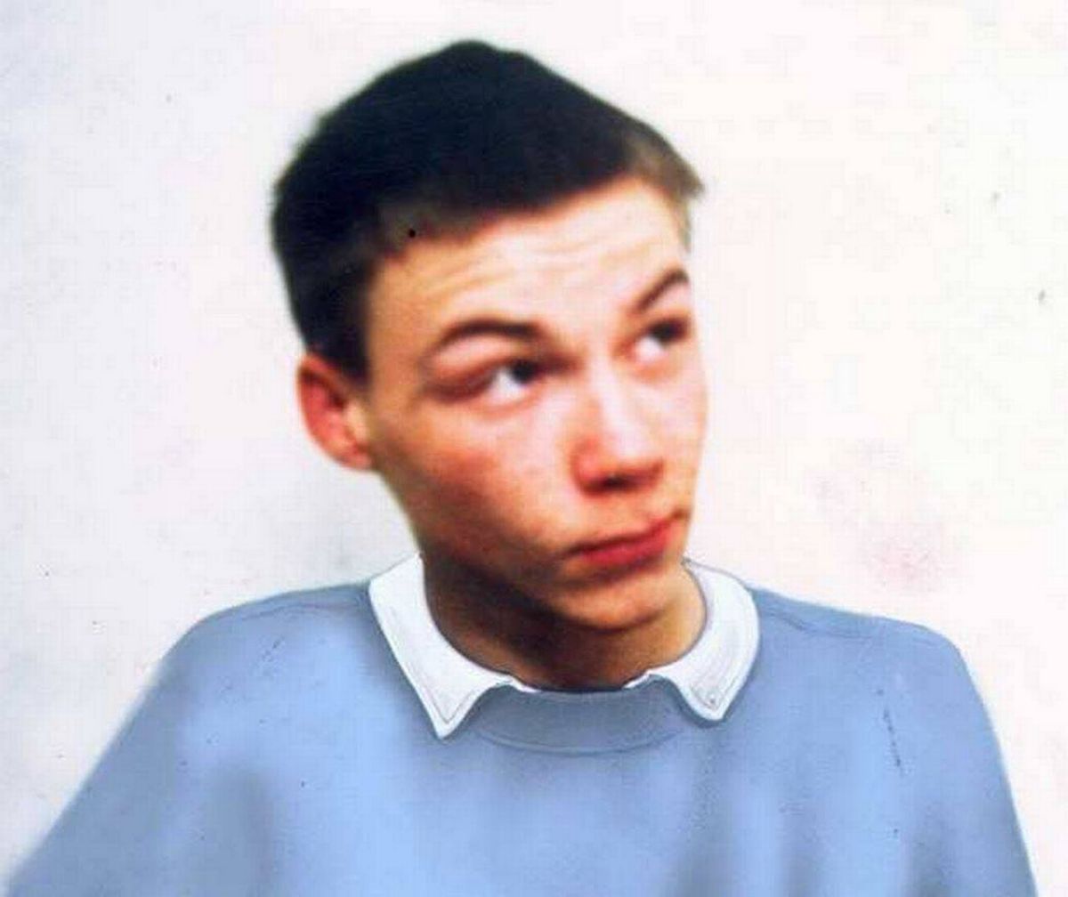 An individual is captured in a portrait, donning a blue shirt with a white collar. The subject exhibits a contemplative expression, gazing towards the upper left. The background is plain and devoid of any distinctive features.