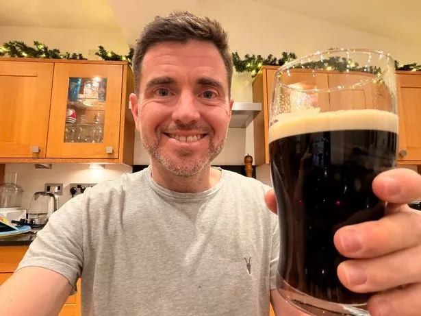 Steffan Rhys takes a selfie while holding up a pint of Guinness in a pint glass to the camera