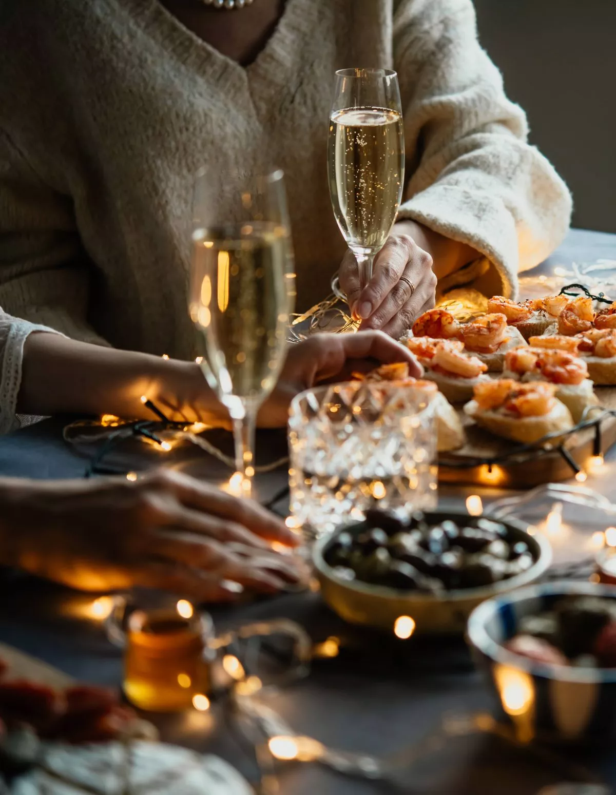 Friends celebrating Christmas or New Year eve party with champagne or sparkling wine.