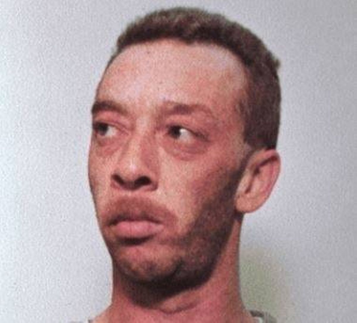 A close-up photograph of an individual with short, dark hair and a facial expression conveying seriousness or contemplation. The person has a light complexion, a well-defined jawline, and is sporting a light beard. The background is plain and white, ensuring the focus remains on the individual's facial features and expression.