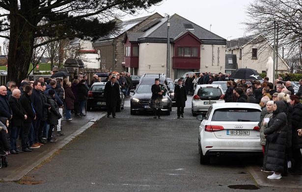 The cortege is piped into the church as mourners line the streets