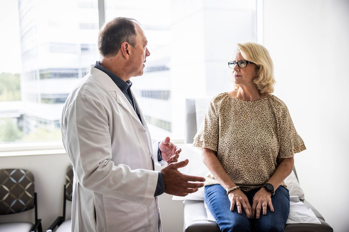 Senior male doctor consulting with senior woman in exam room