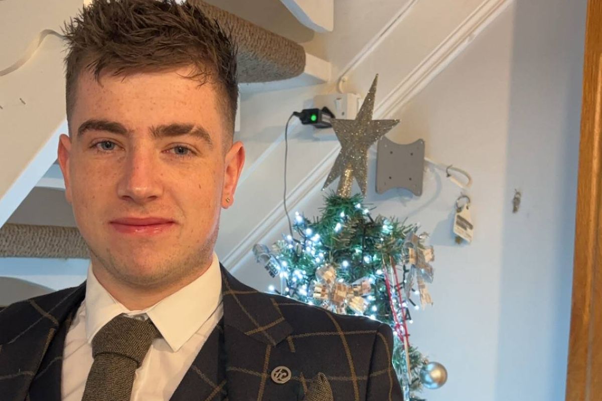 A family photograph of Shea McCabe wearing a suit with a Christmas tree in the background