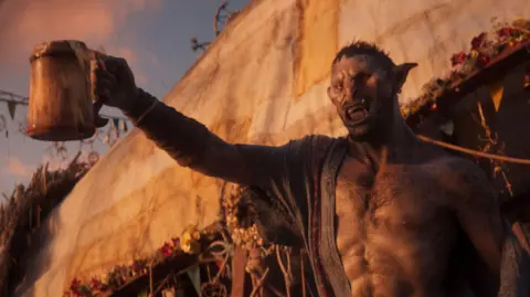 Larian Studios Screenshot from Divinity shows an orc character looking inebriated as he brandishes a large, handled tankard with liquid spilling over the sides. A long-sleeved, button-up top hangs off one shoulder as he toasts something unseen off-screen.