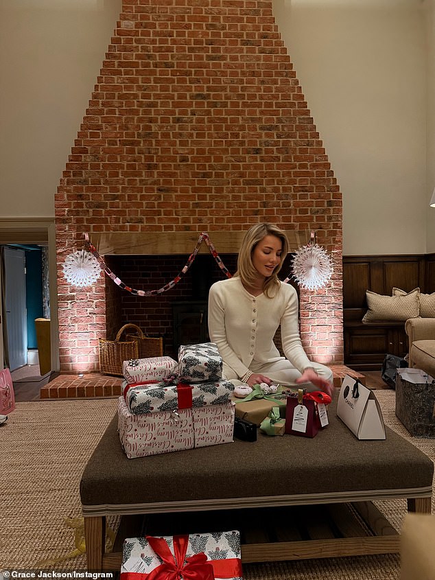The stunner sat in front of a large firplace opening her Christmas presents