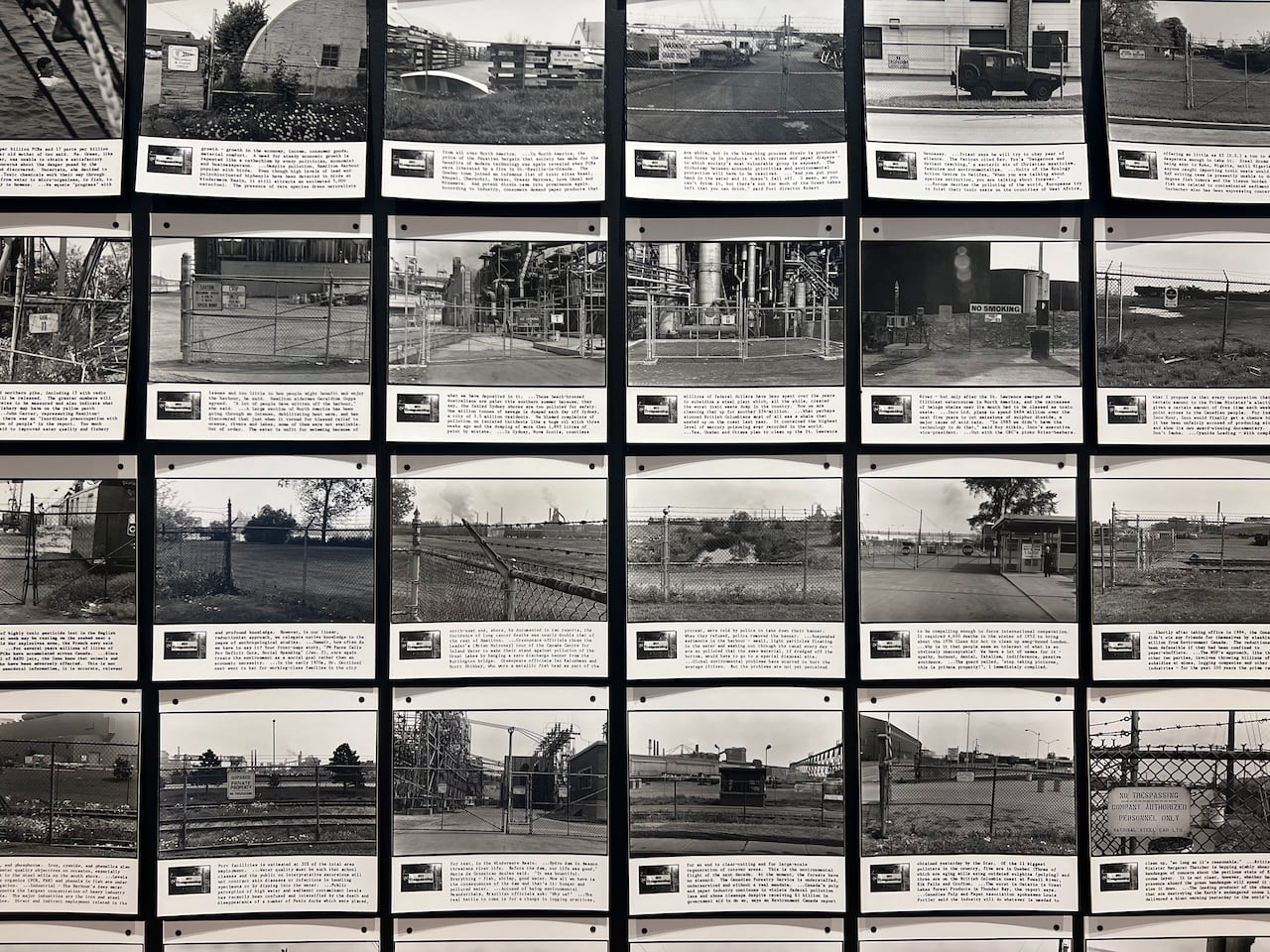 A grid of photographs, each with a block of text, is pinned to the wall. The black-and-white images show a chain link fence in various locales.