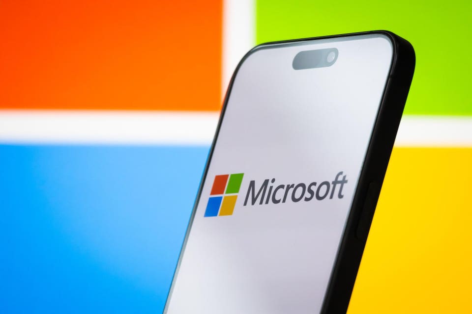 Microsoft logo on smartphone, with logo magnified in background. 