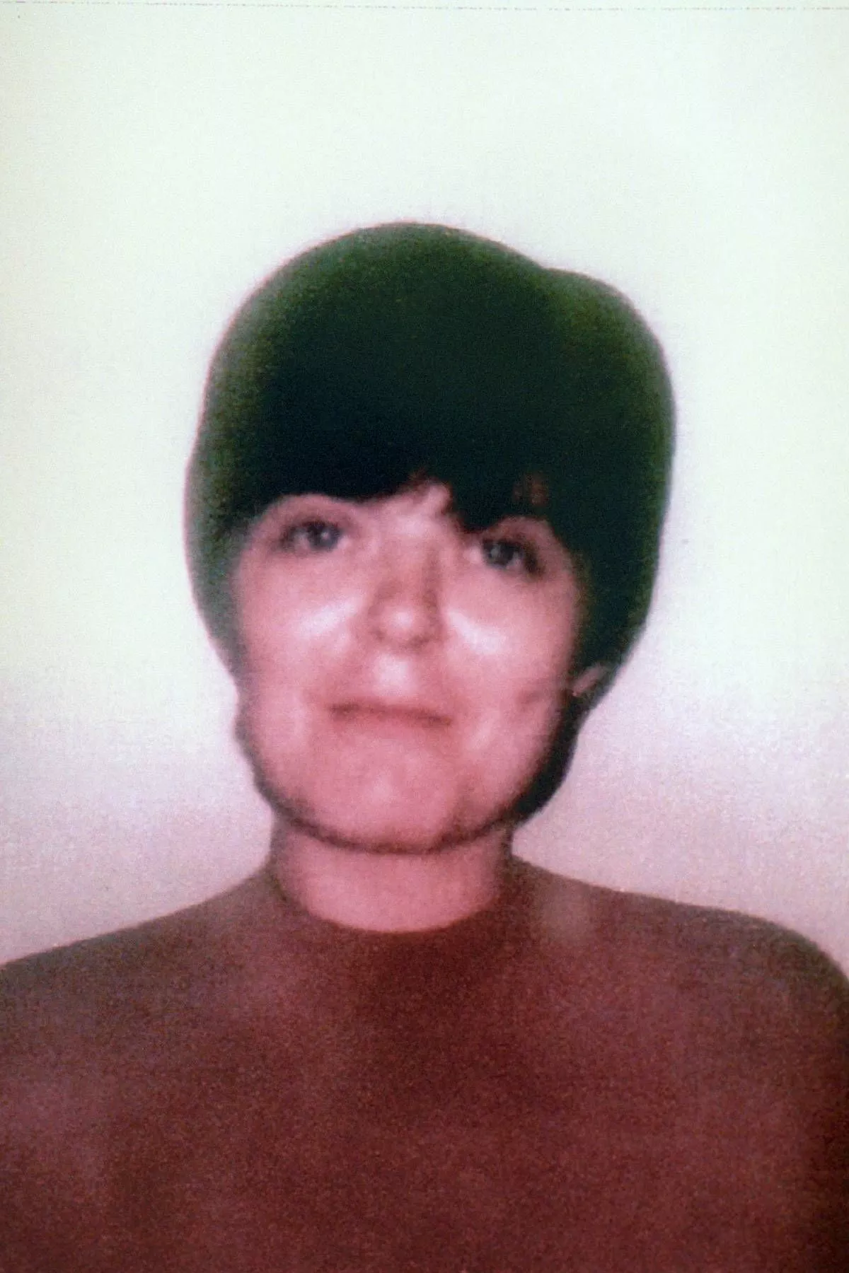 An individual with short, dark hair and a neutral expression is captured in a monochromatic portrait, with a soft, warm background.