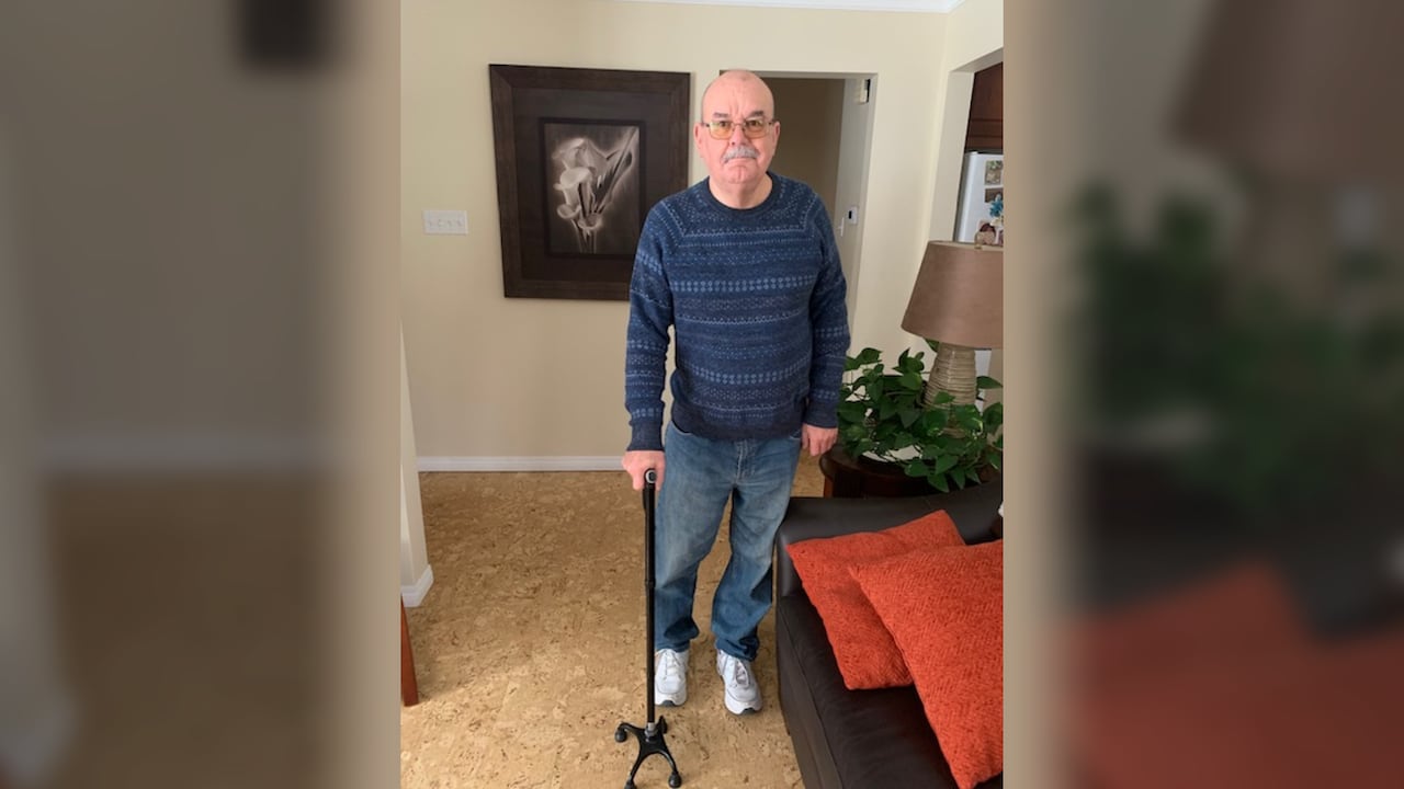 A man holds cane while standing.