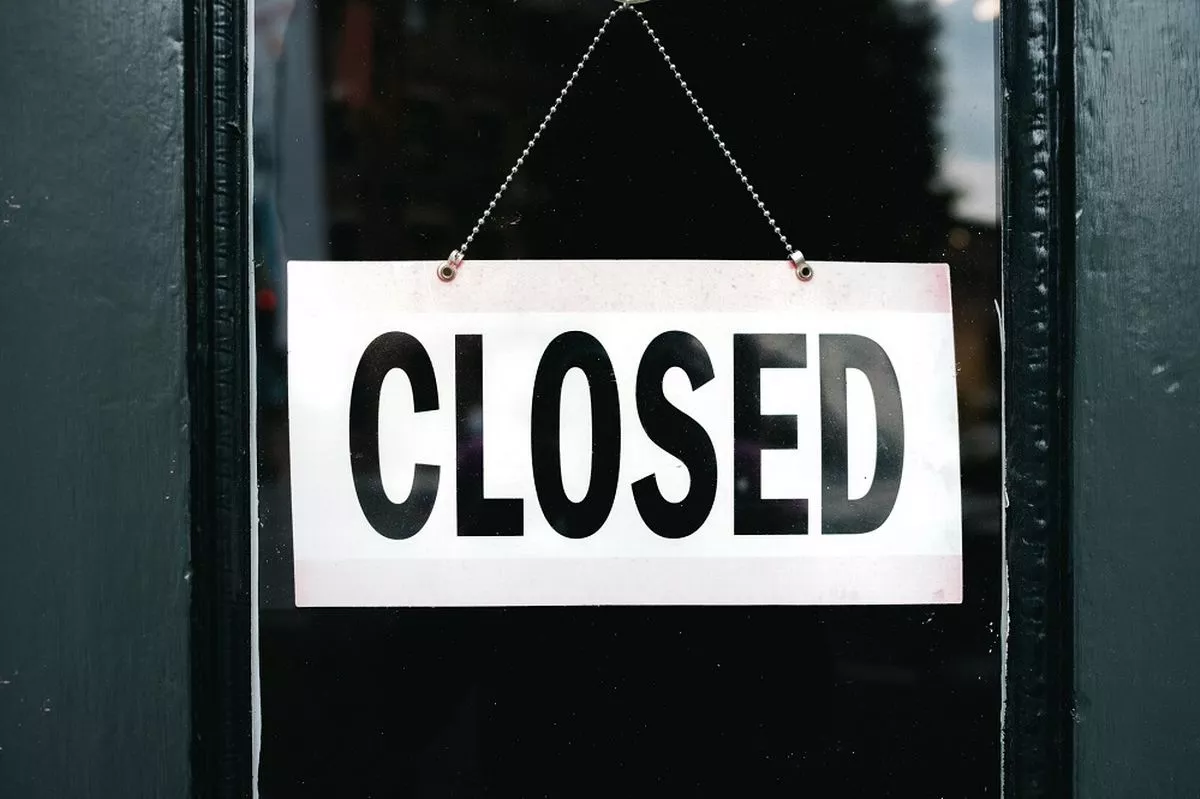 Close-up of "Closed" sign hanging on store’s glass door in a stock image