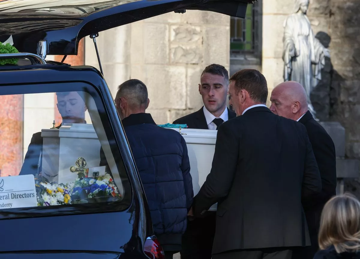Tadhg's tiny white coffin is removed from the hearse. 