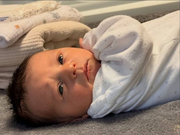 alex gould newborn son in white babygrow