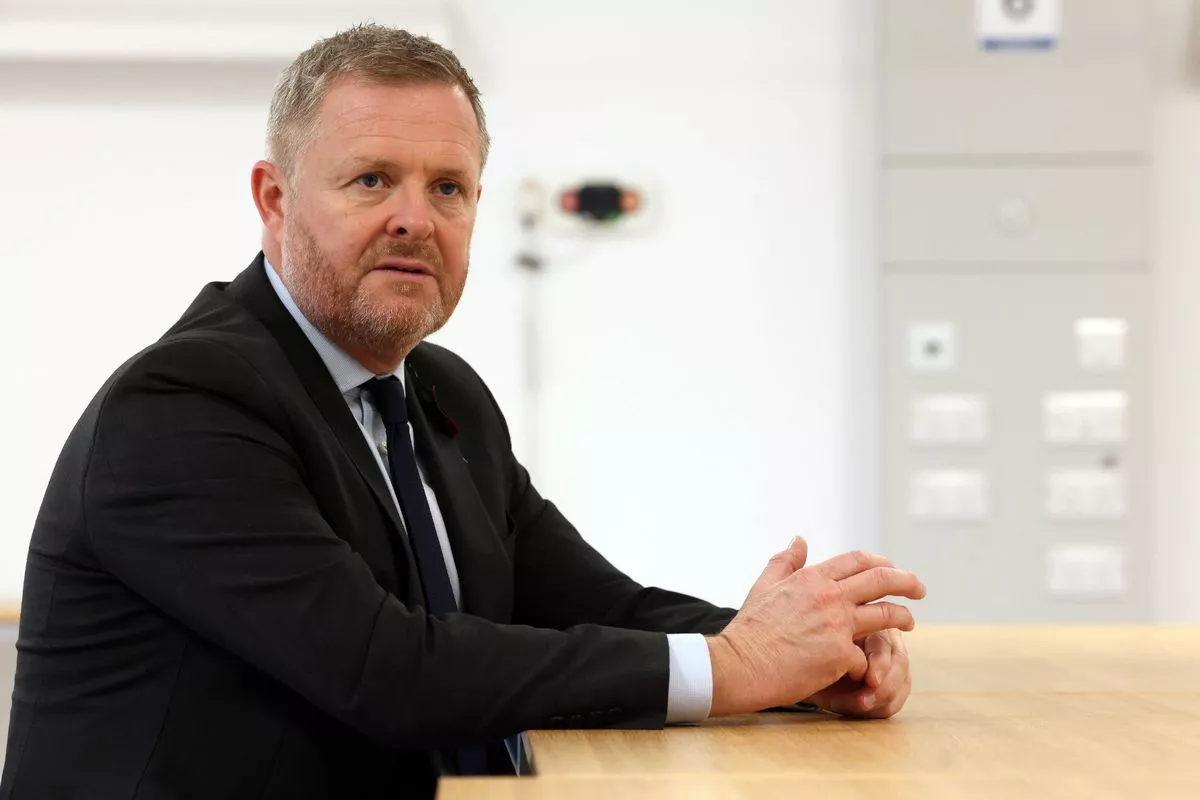 Labour Senedd member Jeremy Miles sitting at desk wearing a black suit and dark tie
