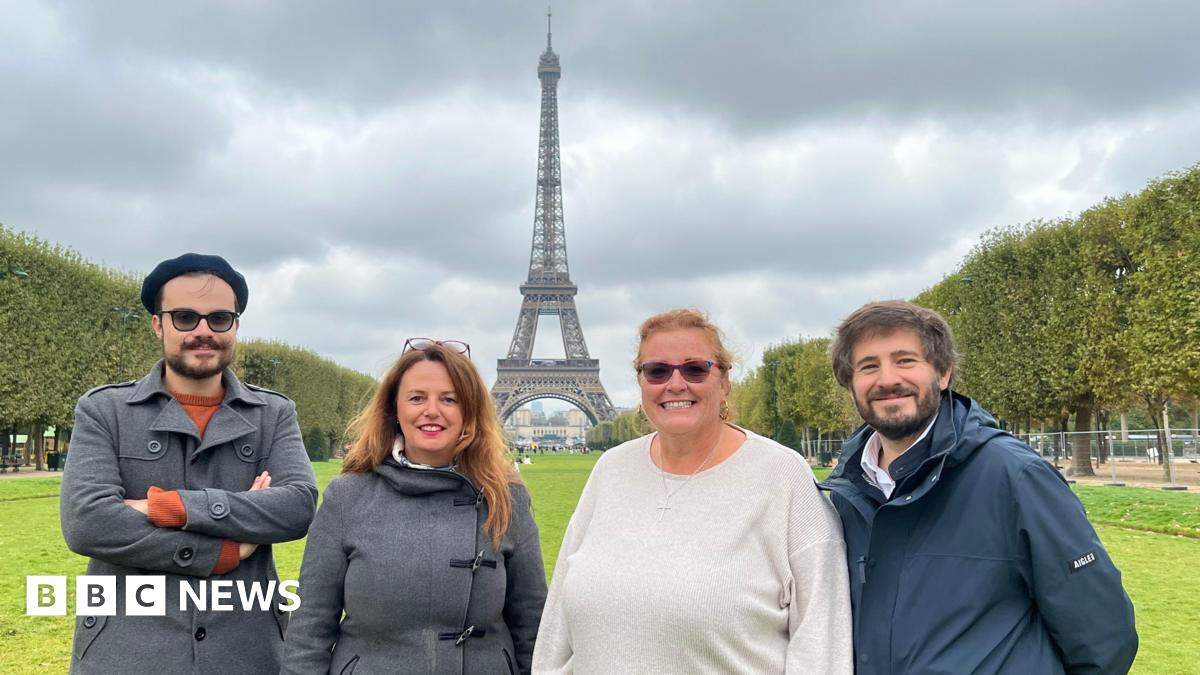 Two men and two women standing in front of the Eiffel Tower in France.