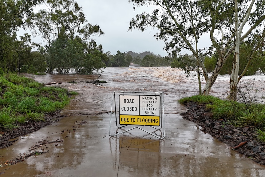 a road closed due to flooding sign in front of a flooded road