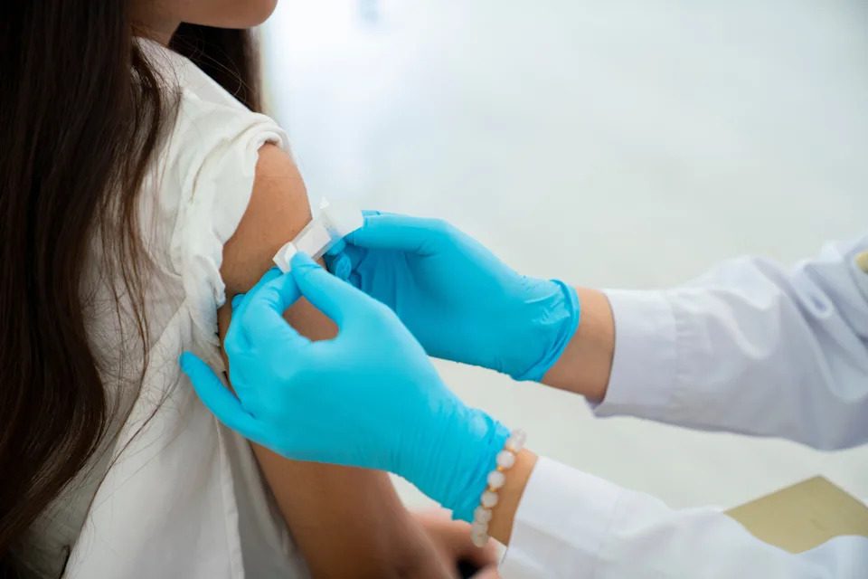 Healthcare worker applies a bandage to a person's upper arm after administering a vaccine or injection