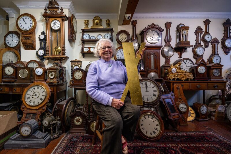 Sitting among a wall of timepieces in Stokes Clocks on MacCurtain Street, Sally Stokes holds a completed numeral destined for Shandon's four-faced liar, reflecting decades of gold-leafing expertise. Picture: Chani Anderson
