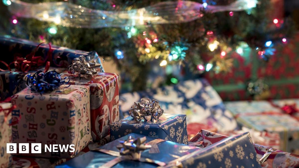Dozens of presents in a variety of wrapping paper under a decorated Christmas tree.