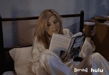 Elliot from "Scrubs" in pajamas cozily sitting in bed in pajamas, reading a book titled "Brock Clarke" and holding a coffee cup