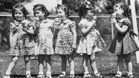 Getty Images five girls in matching dresses licking ice cream cones in this black and white photo from 1938