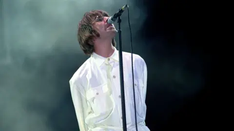 PA Media Liam Gallagher of Oasis in a white shirt and trousers