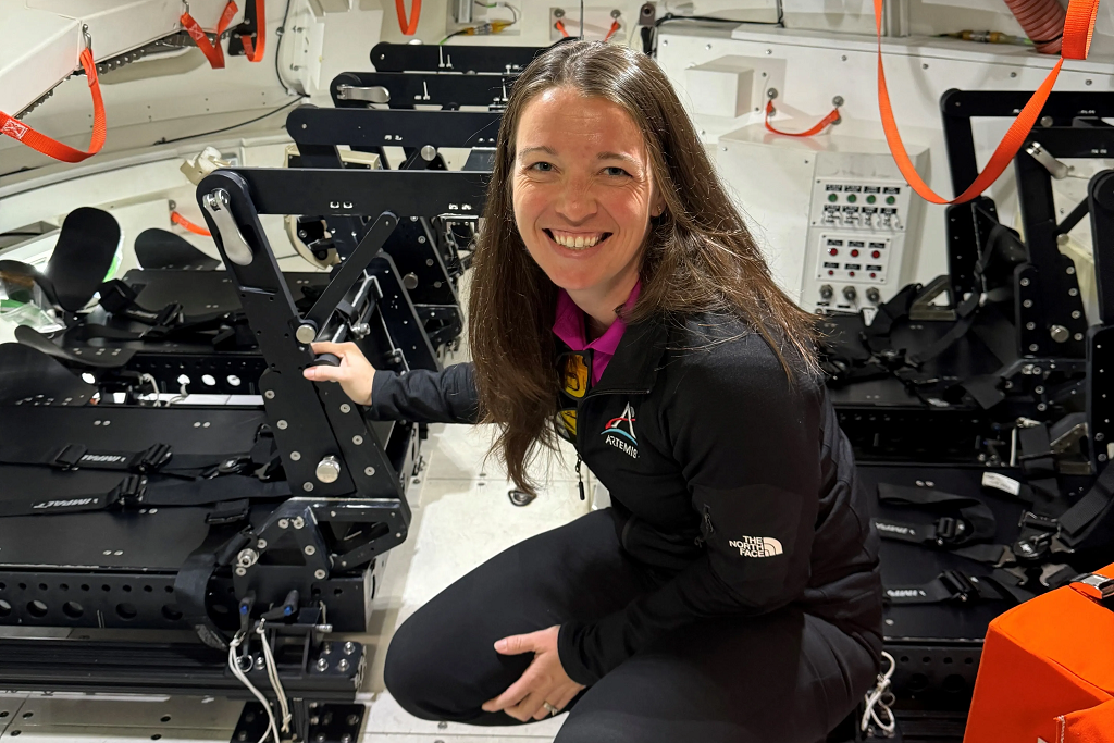 Branelle Rodriguez crouches inside training version of Orion spacecraft