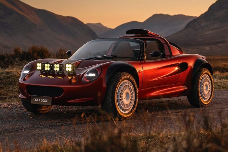 A red sports car with off-road tires and a roof scoop sits on a rural road at sunset, mountains beyond. Its license plate reads "GET LOST," echoing the spirit of 20 Cars That Focused on Analog engagement in 2025.