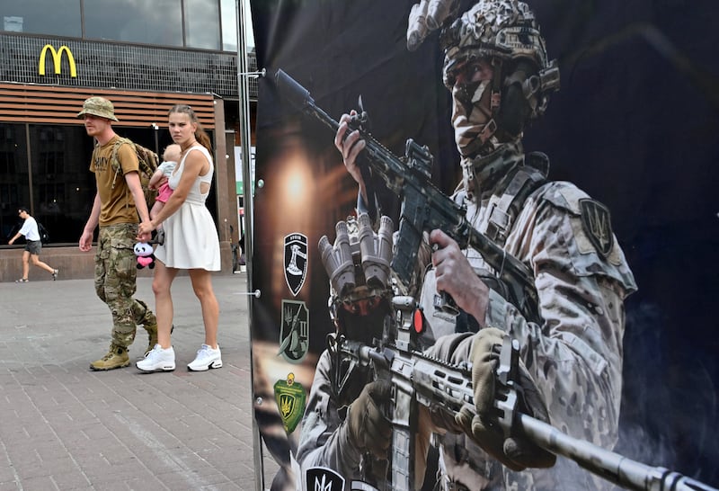 A Ukrainian serviceman and his partner carrying a baby walk past a recruiting point of the 4th Brigade of the Operational Assignment "Rubizh" in Kyiv on July 4, 2024(stock image). Photograph: Sergei Supinsky/Getty Images