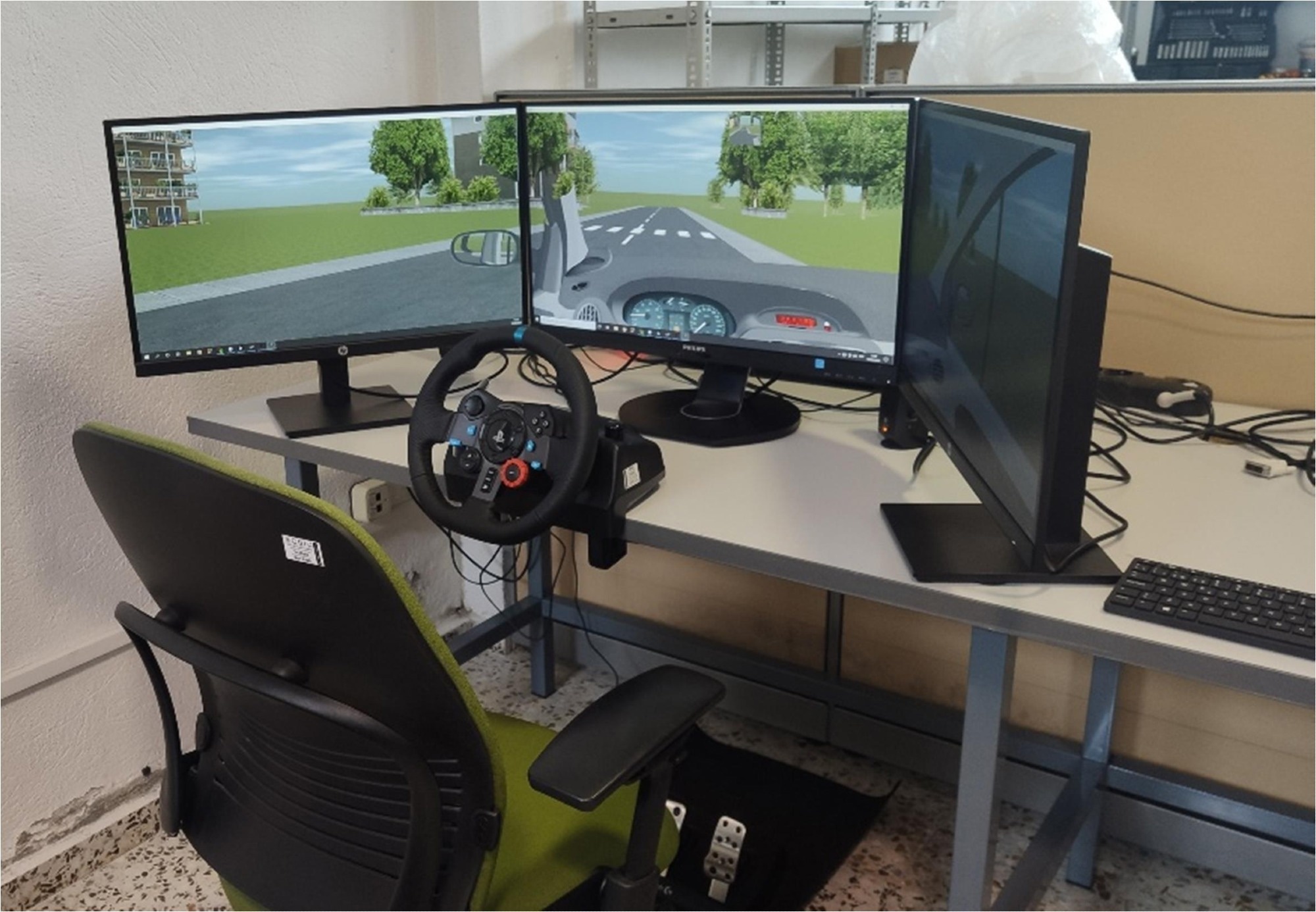 Driving simulator setup used in the experiments, consisting of a steering wheel with pedals, three monitors displaying the virtual driving environment, and a participant’s chair. Study: Cognitive alterations related to driving performance in Parkinson’s disease detected by a driving simulator