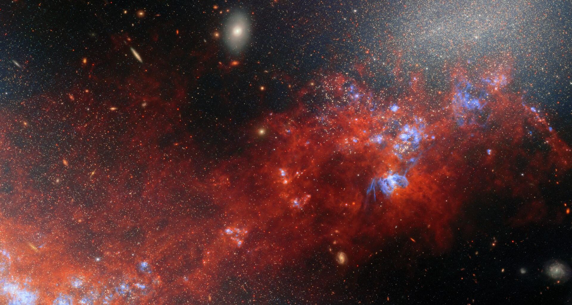 A glowing cloud of red gas and dust mixed in with bright dots for stars in deep space