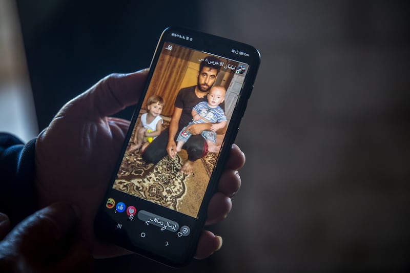 A family member holds a photo of Abdullah Hussein Al-Akhras with his children before he was imprisoned. Photograph: Sally Hayden