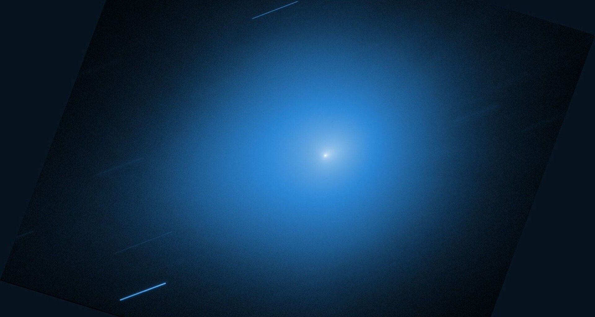 A white light of the comet 3I/ATLAS is surrounded by a blue glow against a black background
