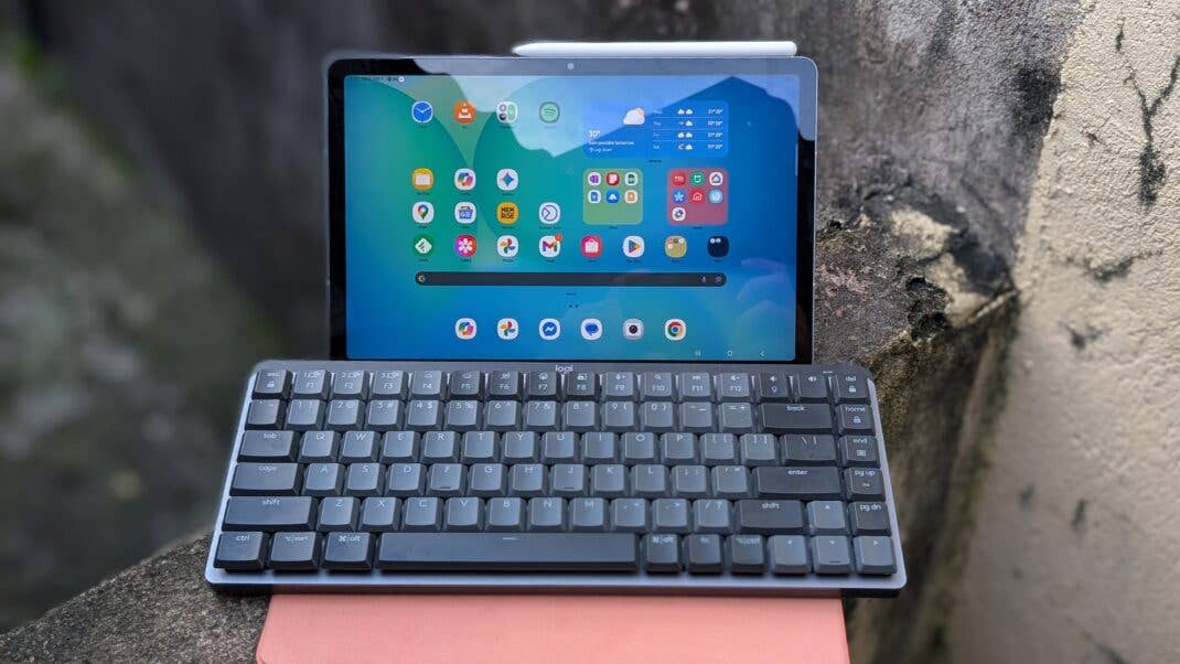 Samsung Galaxy Tab S10 FE on a surface with a keyboard attached, displaying various app icons.